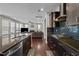 Open concept kitchen with dark wood cabinets, granite countertops, and stainless steel appliances leading to the living room at 1840 Flint Valley Ln, Apex, NC 27502