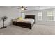 Bright main bedroom with a decorative tray ceiling, ceiling fan, large bed, and lots of windows offering natural light at 1840 Flint Valley Ln, Apex, NC 27502