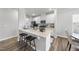 Modern kitchen featuring white cabinets, stainless steel appliances, quartz countertop island with stool seating and stylish hardwood floors at 20 Carolina Maple Dr, Franklinton, NC 27525