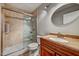 Bright bathroom features a tiled shower with a glass door, a sink with wooden cabinets, and an oval mirror at 201 Dunhagan Pl, Cary, NC 27511