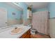 Well-lit bathroom with a single sink vanity, toilet, and shower with patterned curtain at 2024 Country Trails Dr, Clayton, NC 27520