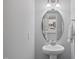 Powder room featuring pedestal sink, oval mirror, and view into kitchen at 205 Fig Tree Bnd, Zebulon, NC 27597