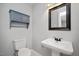 Cozy half bathroom with pedestal sink, gray cabinet, mirror, and toilet at 2120 Hillock Dr, Raleigh, NC 27612