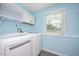 Light filled laundry room features washer, dryer, storage cabinets, and window at 2120 Hillock Dr, Raleigh, NC 27612