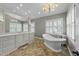 Bright main bathroom featuring double sinks, a standalone tub, natural light, and custom tile flooring at 213 Lewiston Ct, Cary, NC 27513