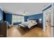 Stylish main bedroom features blue walls, hardwood floors, a king bed, and bright natural light from the windows at 213 Lewiston Ct, Cary, NC 27513