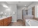 The bright bathroom features a separate tub and shower, a wood vanity, and tile floors at 232 Vinewood Pl, Holly Springs, NC 27540