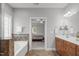 Bright bathroom featuring a soaking tub, spacious vanity, and doorway leading to the main bedroom at 232 Vinewood Pl, Holly Springs, NC 27540