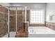 This bathroom features a luxurious bathtub, a glass-enclosed shower, and beautiful tile at 232 Vinewood Pl, Holly Springs, NC 27540