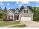 Charming home with red shutters, a two-car garage, and manicured lawn against a blue sky with light clouds at 232 Vinewood Pl, Holly Springs, NC 27540