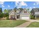 Charming single-Gathering home with two-car garage, green lawn, mature trees, and a brick-lined driveway at 232 Vinewood Pl, Holly Springs, NC 27540