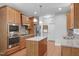 Modern kitchen with an island, stainless steel appliances, built-in oven, and wooden cabinets on hardwood floors at 232 Vinewood Pl, Holly Springs, NC 27540