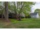Serene backyard with lush greenery, mature trees, and a home featuring a wooden deck and screened porch at 2404 Gillingham Dr, Apex, NC 27539