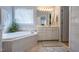 Bright bathroom featuring a soaking tub, double vanity, and tiled flooring at 2404 Gillingham Dr, Apex, NC 27539