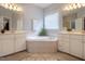 Bright main bathroom featuring soaking tub, double vanity sinks, and neutral tiled floors at 2404 Gillingham Dr, Apex, NC 27539