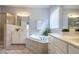 Bright bathroom featuring soaking tub, white cabinets and double vanity sinks and mirrors at 2404 Gillingham Dr, Apex, NC 27539