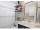 Stylish bathroom with navy vanity, brass fixtures, floating shelves, and a shower curtain at 2651 Mellow Field Dr # 206, Raleigh, NC 27604