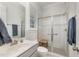 Bright bathroom featuring a glass enclosed shower, gray vanity, and white tiled walls at 2832 Thompson Bluff Dr, Cary, NC 27519