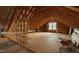 A partially finished attic with visible wood beams is well lit by a central window at 2905 Pluton Pl, Rolesville, NC 27571