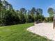 Expansive backyard featuring lush green grass, mature trees, a stone patio, and wrought iron fence at 2905 Pluton Pl, Rolesville, NC 27571