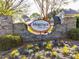 A neighborhood welcome sign featuring stone accents, mature trees, and blooming flowers at 2905 Pluton Pl, Rolesville, NC 27571