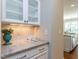 Wet bar area in kitchen features granite countertop, white cabinetry, and updated tile backsplash at 2905 Pluton Pl, Rolesville, NC 27571