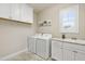 A laundry room features white cabinets, laundry machine and a view to the backyard at 2905 Pluton Pl, Rolesville, NC 27571