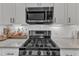 Close up on kitchen stove with stainless steel microwave and white subway tile backsplash at 3 Maple St, Raleigh, NC 27610