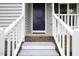 Inviting front entrance with a blue door, white railings, and brick accents on the porch at 300 Round About Rd, Holly Springs, NC 27540