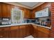A full kitchen with wood cabinets, a white countertop, double sink and an exterior window at 310 Edward Ln, Louisburg, NC 27549