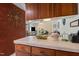Bright kitchen with red brick accent wall, tiled countertops, and dark wood cabinetry at 310 Edward Ln, Louisburg, NC 27549