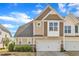 Inviting townhouse featuring a two-car garage and neutral colored siding against a bright blue sky at 318 Acorn Hollow Pl, Durham, NC 27703