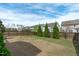 Large backyard featuring a wood fence, green grass, and beautiful landscaping with rows of evergreen trees at 3262 Ripley River Rd, New Hill, NC 27562