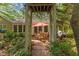 Charming backyard with a brick patio, dining set, and pergola entrance amidst lush greenery at 3417 Windmere Dr, Sanford, NC 27330