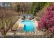 Aerial view of an inground pool with lounge chairs, a pool house with an outdoor bar, and vibrant landscaping at 3908 Yateswood Ct, Raleigh, NC 27603