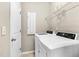 A clean laundry area equipped with a washer, dryer, wire shelving, and a white door at 425 Summit Trail Dr, Hillsborough, NC 27278