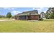 Exterior view of a brick home featuring a screened porch and well-maintained lawn with mature trees at 495 Evans Rd, Princeton, NC 27569