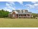 Beautiful brick home with a classic design, expansive lawn, and inviting front porch with white railing at 495 Evans Rd, Princeton, NC 27569