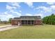 Rear exterior view of a brick home featuring a screened porch, manicured lawn, and mature trees at 495 Evans Rd, Princeton, NC 27569