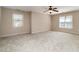 Spacious bedroom with neutral carpet, two windows, a ceiling fan and baseboard trim at 502 Sippihaw Oaks Dr, Fuquay Varina, NC 27526