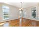 Bright, empty dining room with hardwood floors, a chandelier, and large windows providing ample natural light at 502 Sippihaw Oaks Dr, Fuquay Varina, NC 27526