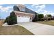 Side view of a brick home featuring an attached garage, green landscaping and a driveway at 502 Sippihaw Oaks Dr, Fuquay Varina, NC 27526