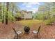 Large backyard featuring an outdoor fire pit, seating area, mature trees, and deck at 5405 Whisperwood Dr, Durham, NC 27713