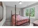 Bright bedroom featuring a four-poster bed with a red and blue floral comforter and a large window at 5405 Whisperwood Dr, Durham, NC 27713