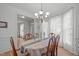 Formal dining room with hardwood floors, decorative chandelier, and large bright windows at 5405 Whisperwood Dr, Durham, NC 27713