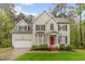 Charming two-story home featuring a bright red front door, well-manicured lawn, and attached two-car garage at 5405 Whisperwood Dr, Durham, NC 27713