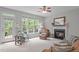 Bright living room featuring a fireplace, ceiling fan, large windows, and access to outdoor deck at 5405 Whisperwood Dr, Durham, NC 27713