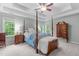 Spacious bedroom featuring a four-poster bed, tray ceilings, and and nightstands at 5405 Whisperwood Dr, Durham, NC 27713