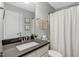 Well-lit bathroom with a modern vanity, dark countertop, and a shower with a neutral-toned curtain at 55 Northdale Ct, Louisburg, NC 27549