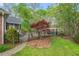 Landscaped backyard including a pergola, stone patio, and screened in back porch at 5900 Orchid Valley Rd, Raleigh, NC 27613